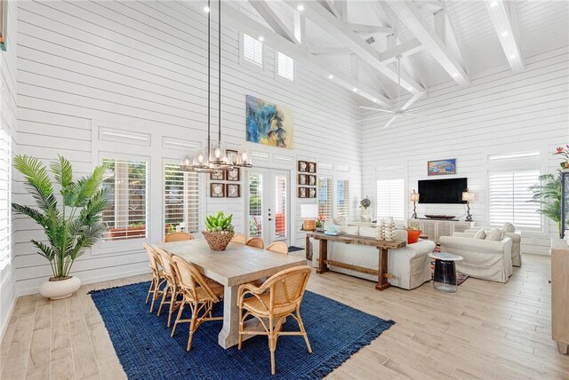 dining room with light wood-type flooring and high vaulted ceiling