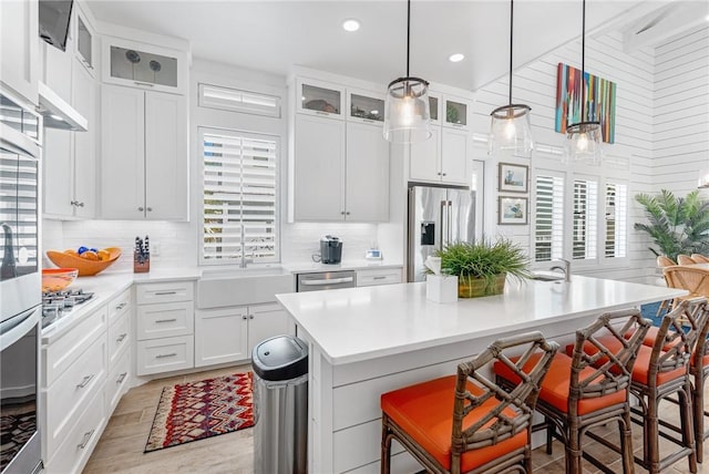 kitchen featuring a center island, a kitchen breakfast bar, sink, appliances with stainless steel finishes, and white cabinetry