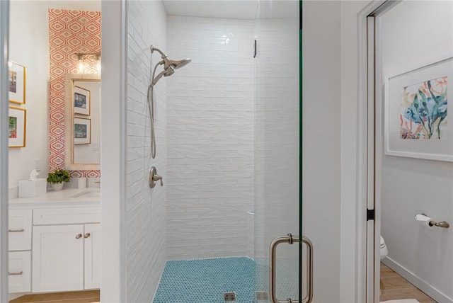 bathroom featuring vanity, toilet, and a shower with shower door