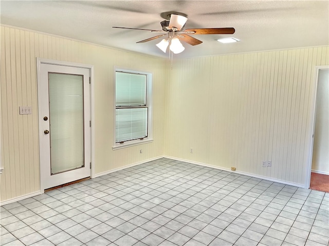 empty room with ceiling fan, wooden walls, and a textured ceiling