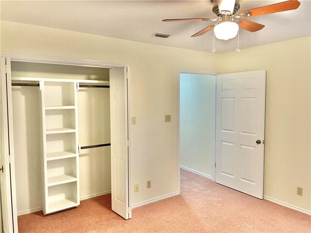 unfurnished bedroom featuring ceiling fan, a textured ceiling, light carpet, and a closet