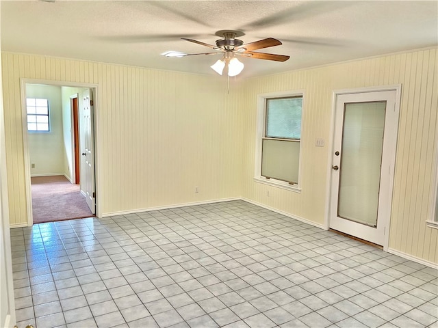 spare room featuring a textured ceiling, ceiling fan, and light tile patterned floors