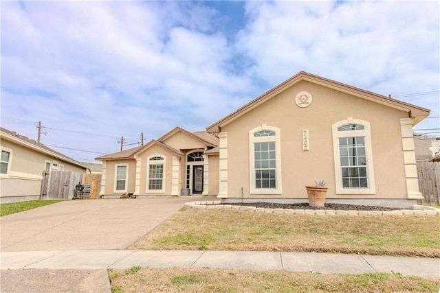 view of front facade with driveway, fence, and stucco siding