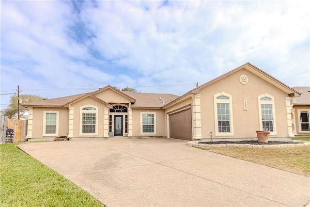 single story home featuring a garage, a front yard, concrete driveway, and stucco siding