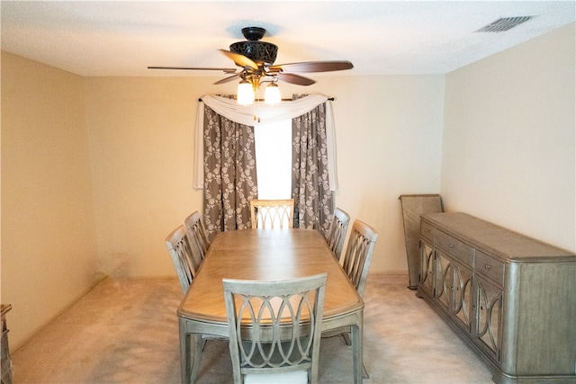 dining area featuring ceiling fan and light colored carpet