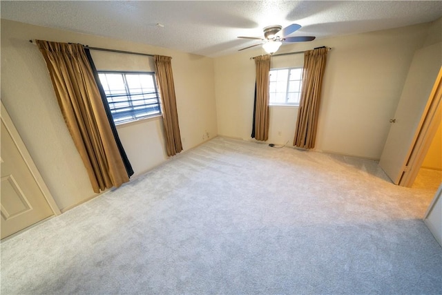 unfurnished bedroom featuring light carpet, a textured ceiling, and ceiling fan