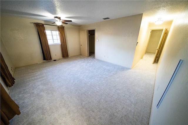 carpeted spare room featuring ceiling fan and a textured ceiling