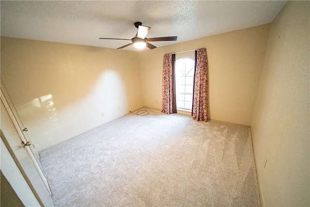 spare room featuring light carpet, ceiling fan, and a textured ceiling