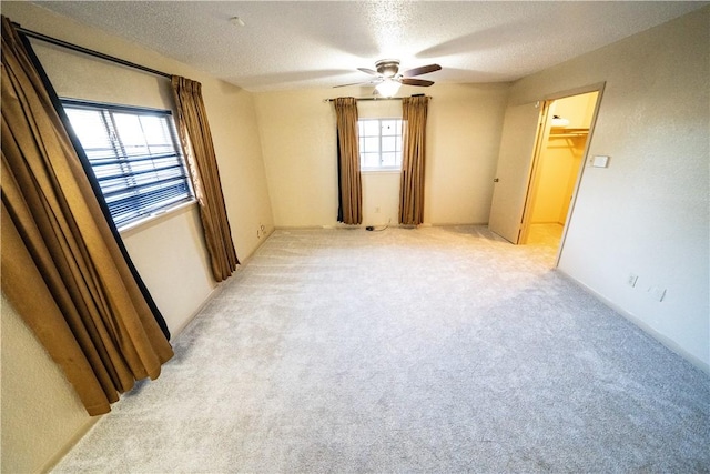 spare room featuring ceiling fan, light colored carpet, and a textured ceiling