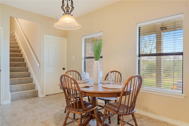 dining space with light tile patterned floors, stairs, and baseboards