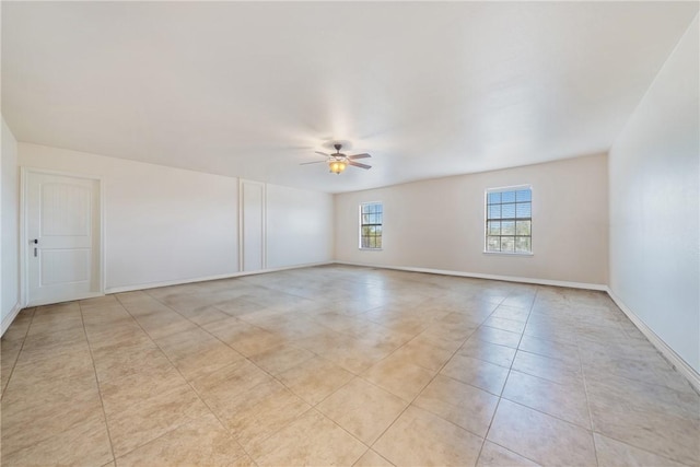 spare room featuring light tile patterned floors, a ceiling fan, and baseboards
