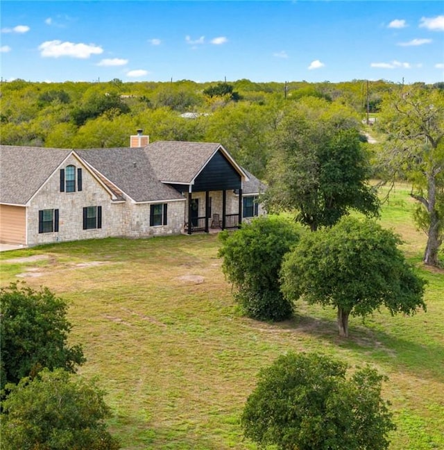 ranch-style house featuring a chimney, a front lawn, and stone siding