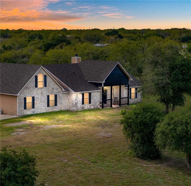 view of front of home featuring roof with shingles, stone siding, and a chimney