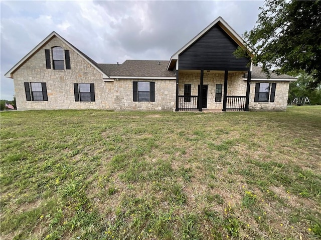 view of front of house with roof with shingles, a front lawn, and stone siding