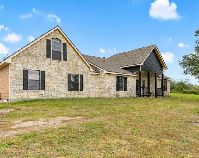 rear view of property with roof with shingles, a yard, and stone siding