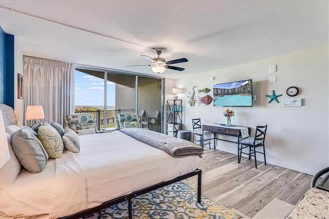 bedroom with ceiling fan, a wall of windows, access to outside, and light hardwood / wood-style flooring