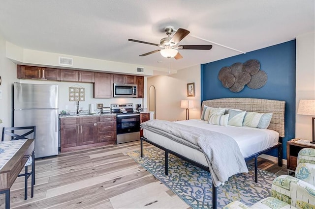 bedroom featuring ceiling fan, light wood-type flooring, sink, and stainless steel refrigerator