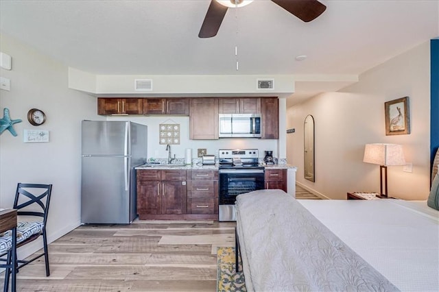 kitchen with appliances with stainless steel finishes, light wood-type flooring, ceiling fan, and sink