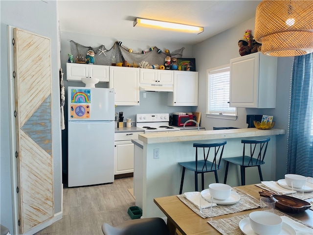 kitchen featuring white cabinetry, kitchen peninsula, white appliances, a breakfast bar, and light wood-type flooring