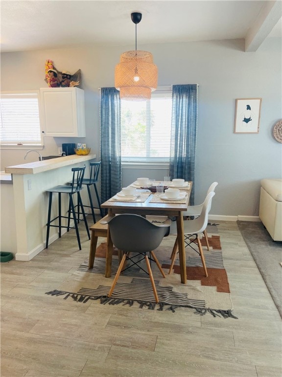 dining area with beamed ceiling and light hardwood / wood-style floors