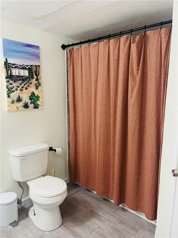 bathroom with walk in shower, wood-type flooring, a textured ceiling, and toilet