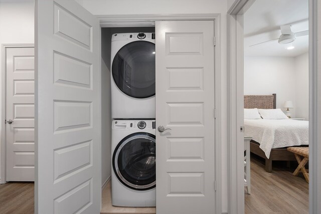 laundry room featuring light wood-type flooring, stacked washer and dryer, and ceiling fan