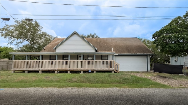 rear view of house featuring a garage, covered porch, and a lawn