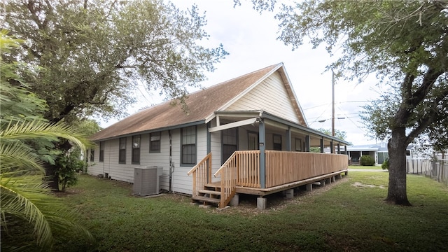 rear view of house with central AC unit, a sunroom, and a yard