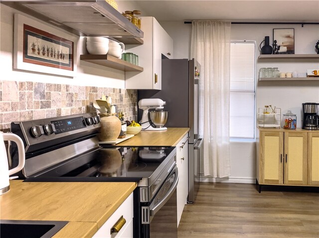 kitchen featuring tasteful backsplash, wall chimney range hood, wood-type flooring, and electric range