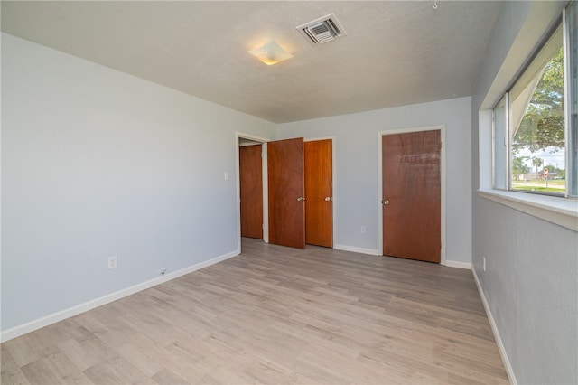 unfurnished bedroom featuring light wood-type flooring and a textured ceiling