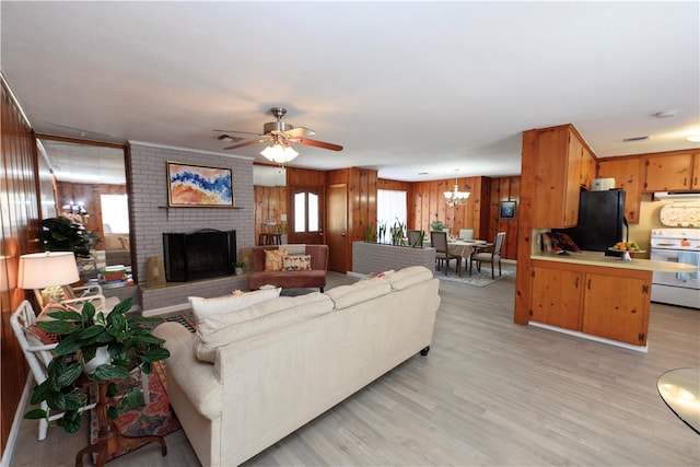 living room featuring a fireplace, light hardwood / wood-style floors, wooden walls, and ceiling fan with notable chandelier