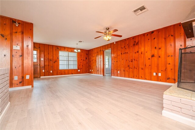 unfurnished living room featuring light hardwood / wood-style floors, wooden walls, and ceiling fan