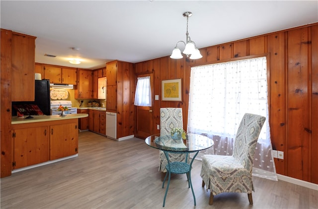 dining room with light hardwood / wood-style flooring, wooden walls, and an inviting chandelier