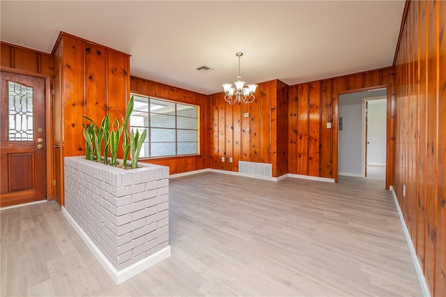 entryway featuring hardwood / wood-style floors, wood walls, and a chandelier