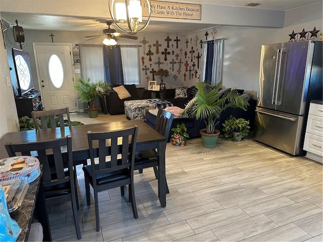 dining space with ceiling fan with notable chandelier