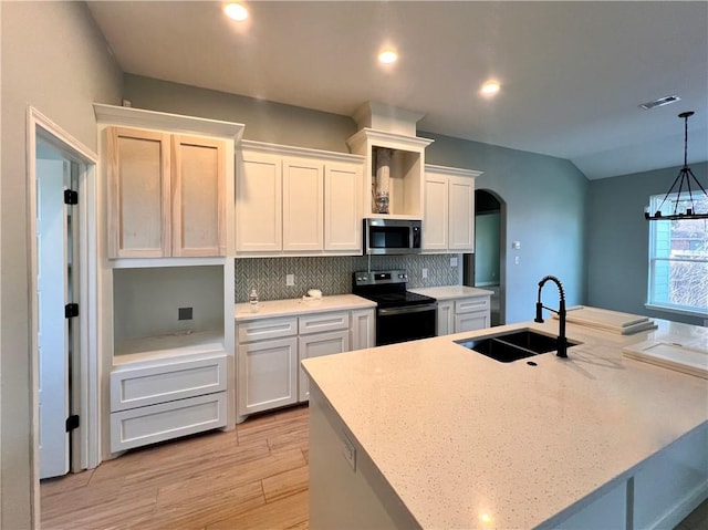 kitchen featuring pendant lighting, white cabinetry, an island with sink, sink, and black / electric stove