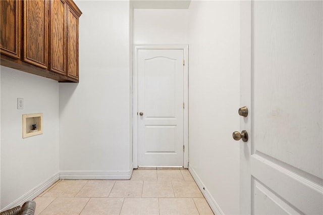 clothes washing area with washer hookup, cabinet space, baseboards, and light tile patterned flooring