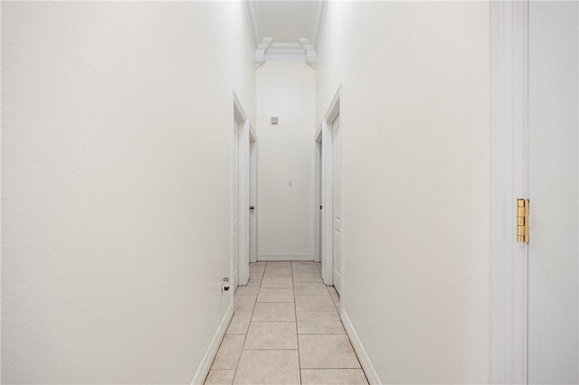 corridor with light tile patterned floors, baseboards, and ornamental molding