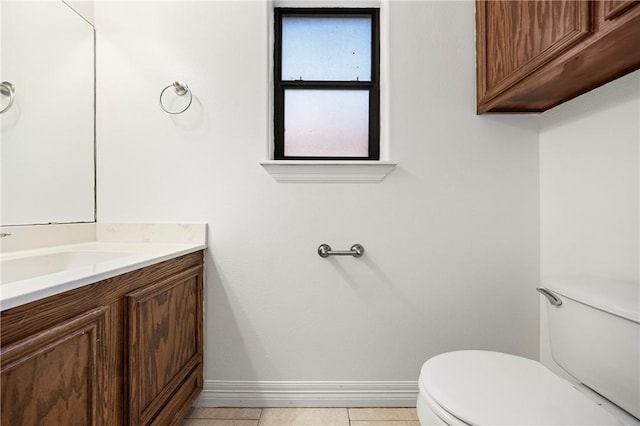 half bathroom with toilet, tile patterned flooring, baseboards, and vanity