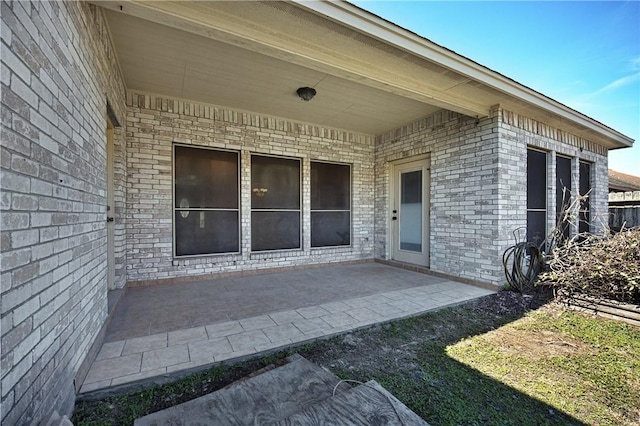 doorway to property with a patio and brick siding