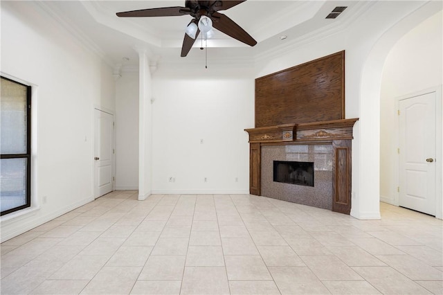 unfurnished living room with ornamental molding, a tile fireplace, a raised ceiling, and visible vents