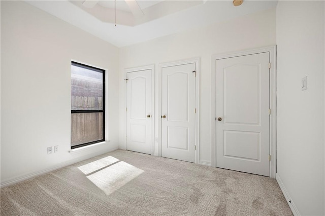 unfurnished bedroom featuring carpet, baseboards, and a raised ceiling