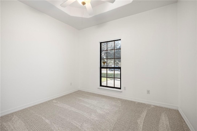 spare room featuring carpet floors, a tray ceiling, a ceiling fan, and baseboards