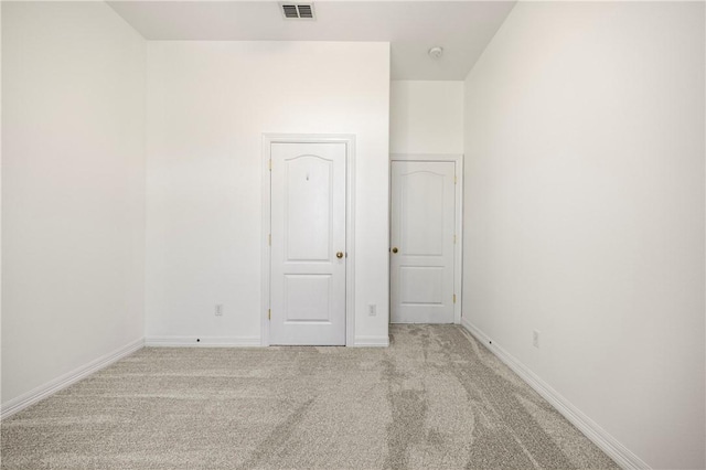 unfurnished room featuring baseboards, visible vents, and light colored carpet