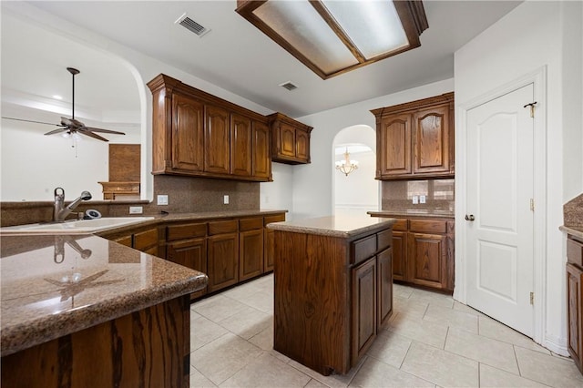 kitchen featuring arched walkways, ceiling fan with notable chandelier, a sink, and visible vents