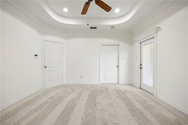 carpeted empty room with a raised ceiling, visible vents, ornamental molding, ceiling fan, and baseboards