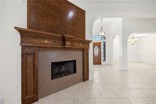 living area with arched walkways, a decorative wall, a fireplace, ornamental molding, and wainscoting