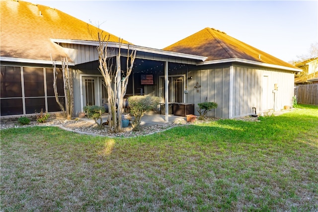 rear view of house featuring a patio, a yard, fence, and a sunroom