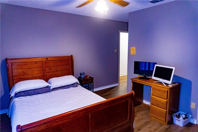 bedroom with ceiling fan, baseboards, a textured ceiling, and wood finished floors