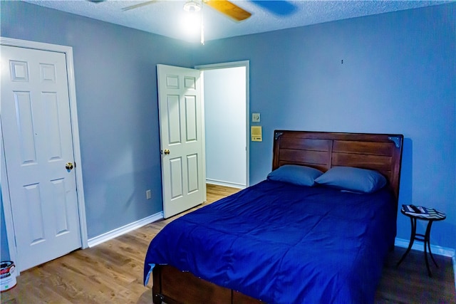 bedroom with a textured ceiling, a ceiling fan, baseboards, and wood finished floors